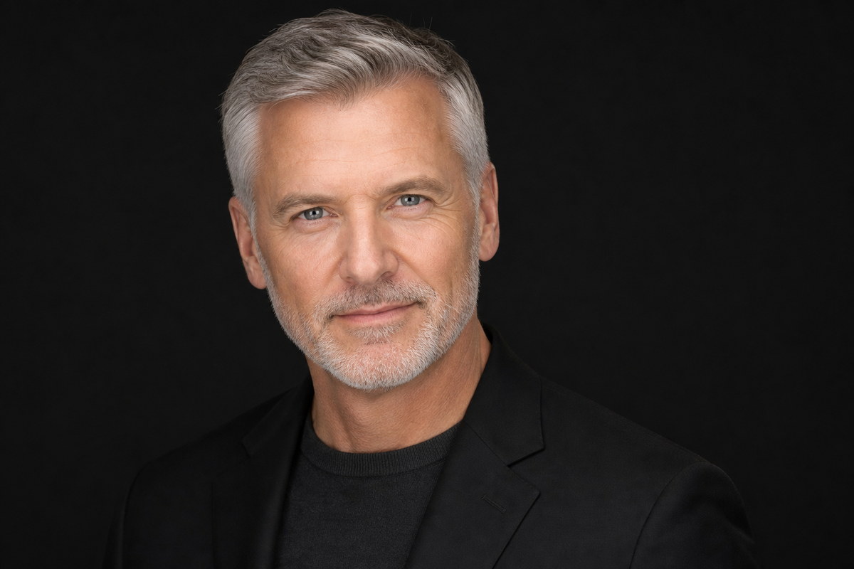 Professional headshot in a dark jacket against a dark studio background.